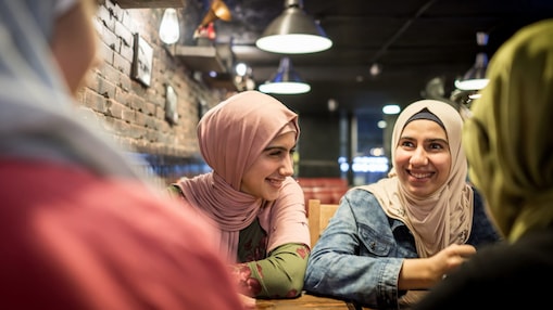 Dos mujeres sentadas en una mesa sonriendo