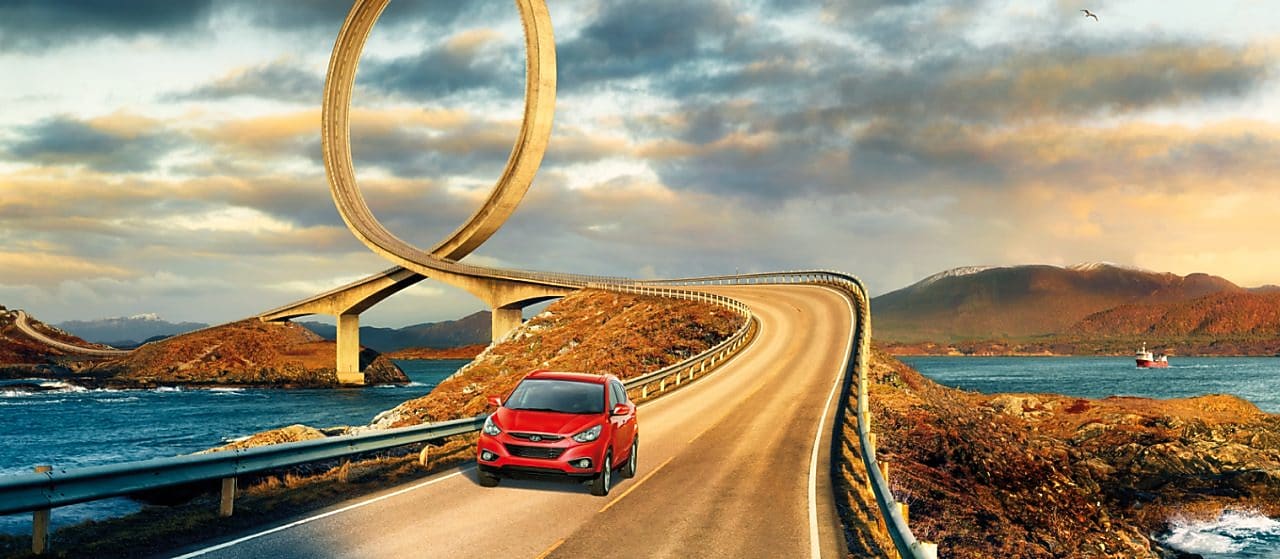 Auto rojo circulando por la ruta junto al río