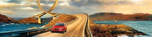 Auto rojo circulando por la ruta junto al río